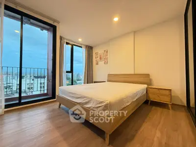 Spacious bedroom with modern decor and city view balcony in urban apartment