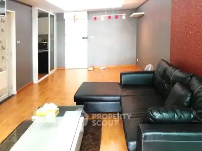 Spacious modern living room with sleek black leather sofa and wooden flooring