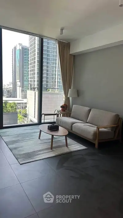 Modern living room with large windows offering city view, stylish furniture, and natural light.