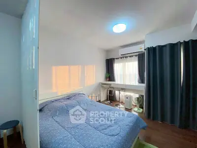 Cozy bedroom with modern decor, large window, and ample natural light in a stylish apartment.