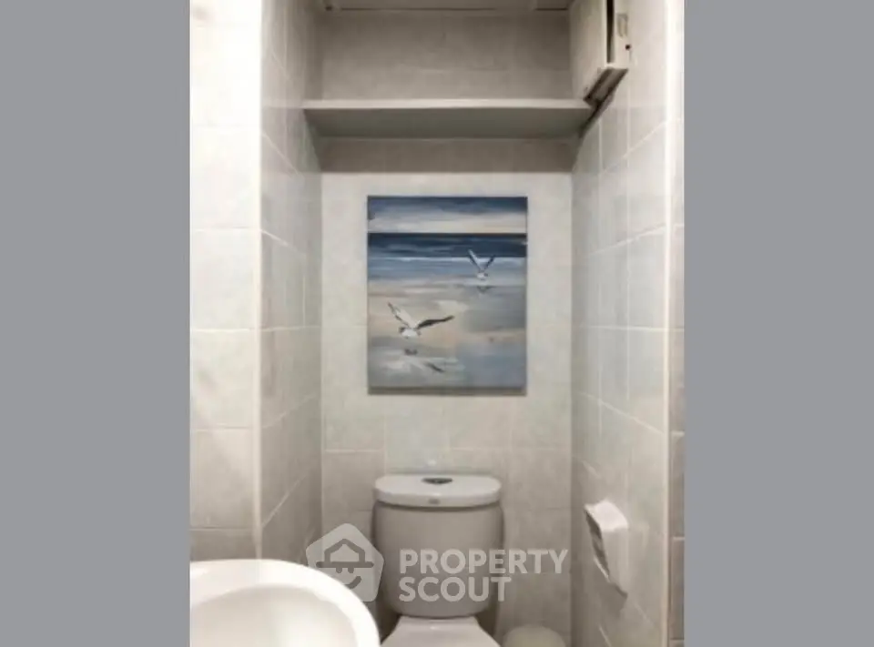 Compact bathroom with modern fixtures and serene ocean artwork.