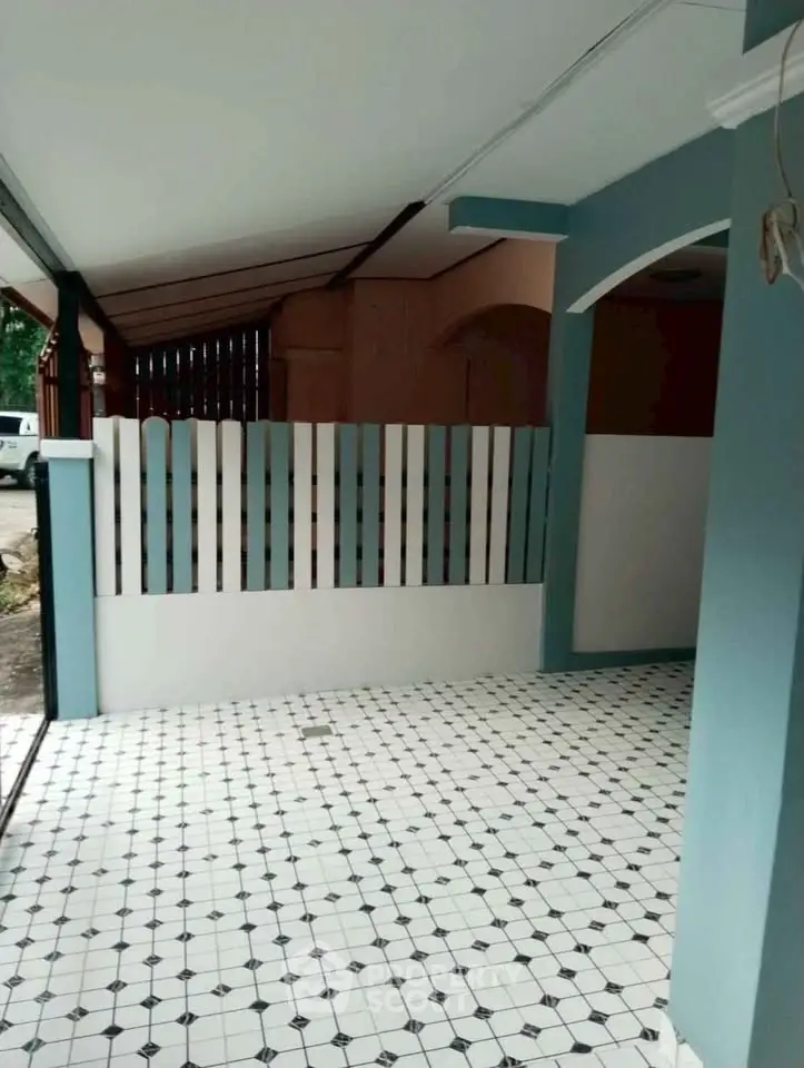 Charming covered patio with stylish tiled flooring and decorative fencing, perfect for outdoor relaxation.