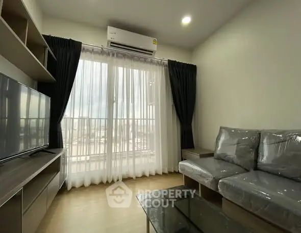 Modern living room with large window and sleek furniture in a cozy apartment.