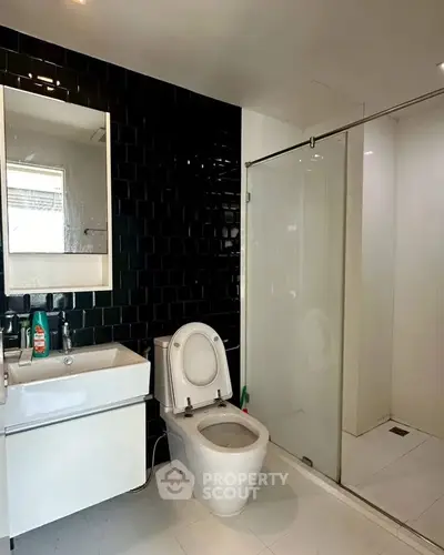 Modern bathroom with sleek black tiles and glass shower enclosure