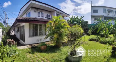 Charming two-story house with lush garden and tropical plants, perfect for nature lovers seeking tranquility.