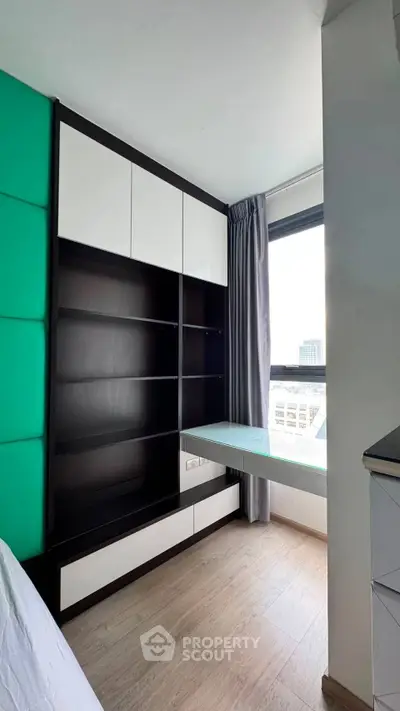 Modern study room with built-in shelving and large window offering city views.