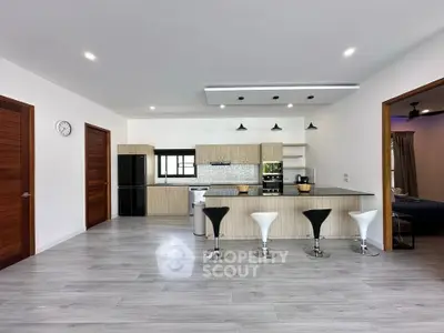 Spacious modern kitchen with sleek island and bar stools, featuring contemporary design and ample natural light.