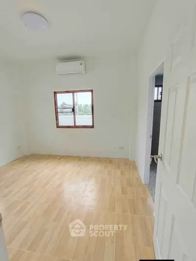 Spacious empty room with wooden flooring and air conditioning, perfect for customization.