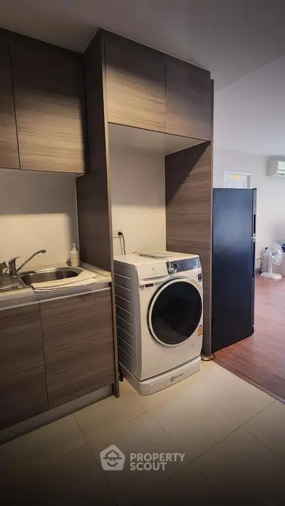 Modern kitchen with sleek cabinetry and built-in washing machine, perfect for urban living.