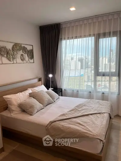Modern bedroom with city view, featuring stylish decor and natural light through large windows.
