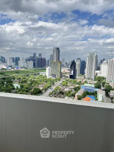 Stunning cityscape view from high-rise balcony overlooking urban skyline and lush greenery.
