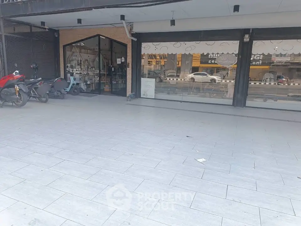 Spacious commercial storefront with large glass windows and ample parking space.