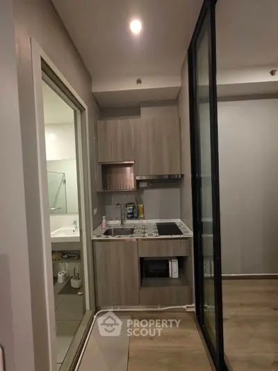 Modern compact kitchen with sleek cabinetry and built-in appliances in a stylish apartment.