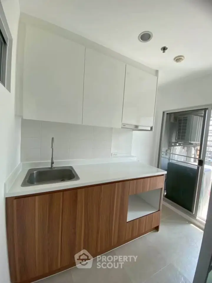 Modern kitchen with sleek cabinetry and stainless steel sink in a bright apartment.
