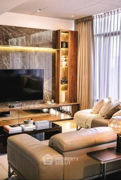 Luxurious living room with modern decor, large TV, and elegant lighting.