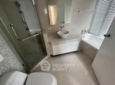 Modern bathroom with sleek fixtures, glass shower, and bathtub in a stylish real estate property.