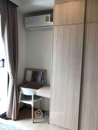 Cozy bedroom corner with built-in wardrobe and study desk, featuring natural light and modern air conditioning.