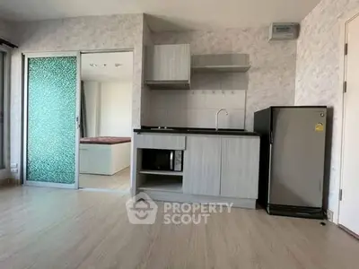 Modern studio apartment with compact kitchen and sliding glass door to bedroom.