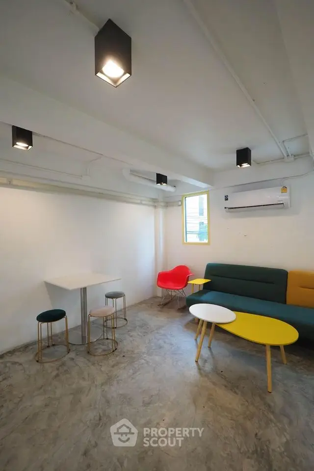 Modern minimalist living room with colorful furniture and concrete floor