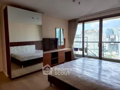 Spacious bedroom with city view and modern furnishings in high-rise apartment.