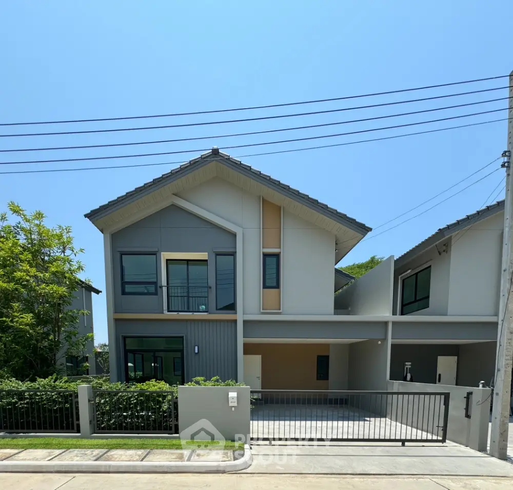 Modern two-story house with gated driveway and lush greenery