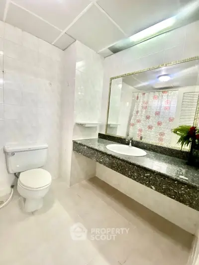 Spacious bathroom with elegant granite countertop and large mirror