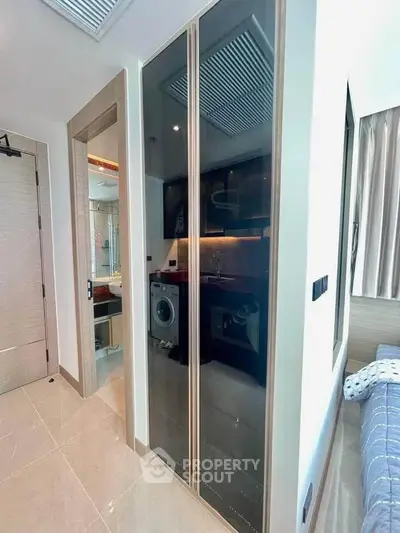 Modern apartment interior with sleek kitchen and washing machine, showcasing contemporary design and functionality.