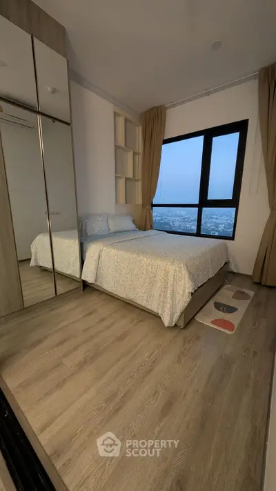 Cozy bedroom with city view, mirrored wardrobe, and elegant wooden flooring.