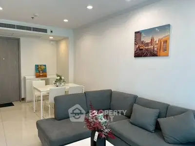 Modern living room with stylish gray sofa and elegant dining area in open layout apartment.