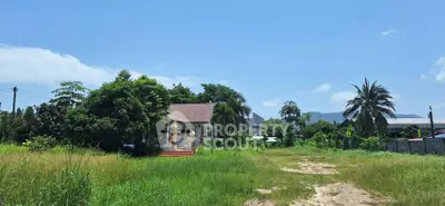 Charming rural property with lush greenery and spacious land under clear blue skies.