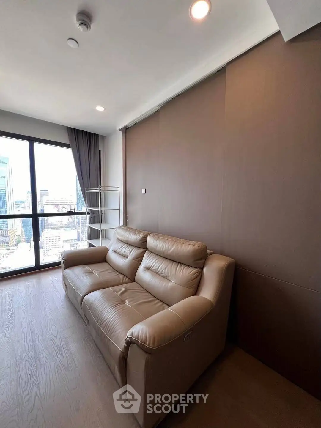 Modern living room with leather sofa and city view from large window.