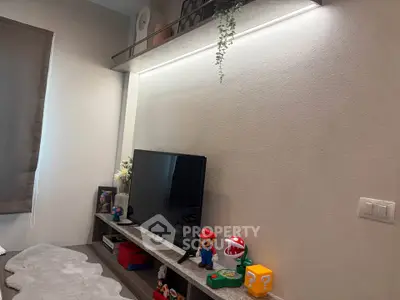 Modern living room with stylish decor and entertainment setup featuring a TV and playful accents.