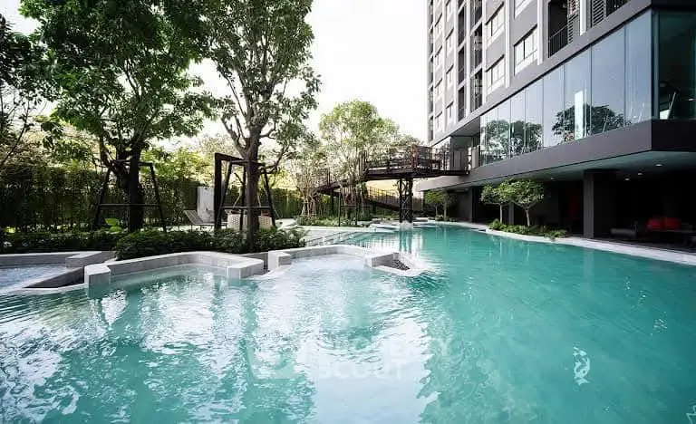 Luxurious residential pool area with modern building and lush greenery