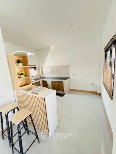 Modern kitchen with open layout and sleek design, featuring a breakfast bar and ample natural light.