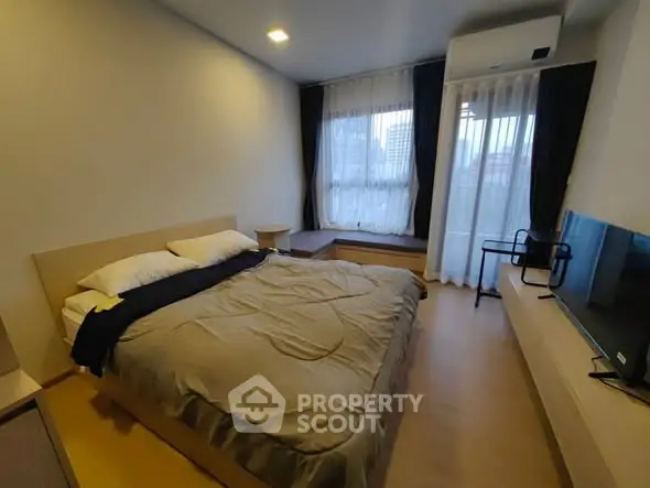 Cozy bedroom with large window and modern furnishings in a stylish apartment.