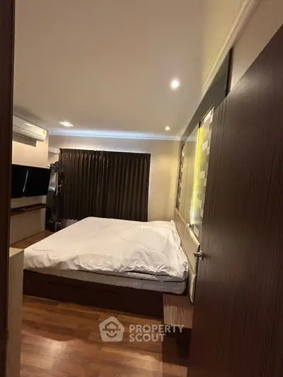 Cozy bedroom with modern decor and ambient lighting, featuring a comfortable bed and sleek wooden flooring.