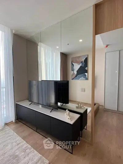 Modern living room with sleek TV stand and abstract art, featuring floor-to-ceiling windows and elegant decor.