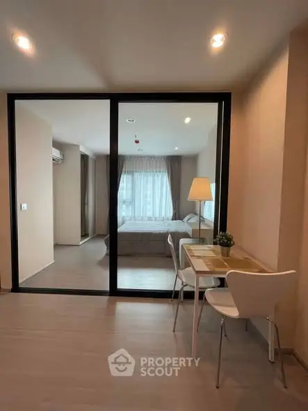 Modern apartment interior with glass partition, cozy bedroom, and stylish dining area.