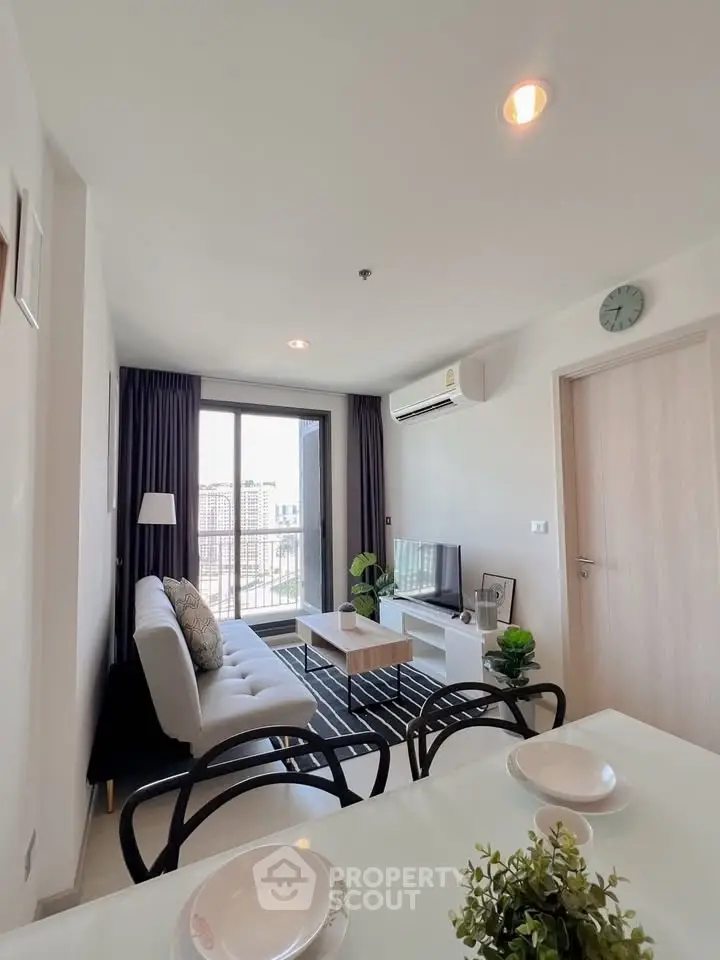 Modern living room with stylish decor and city view, featuring a cozy sofa and sleek TV setup.