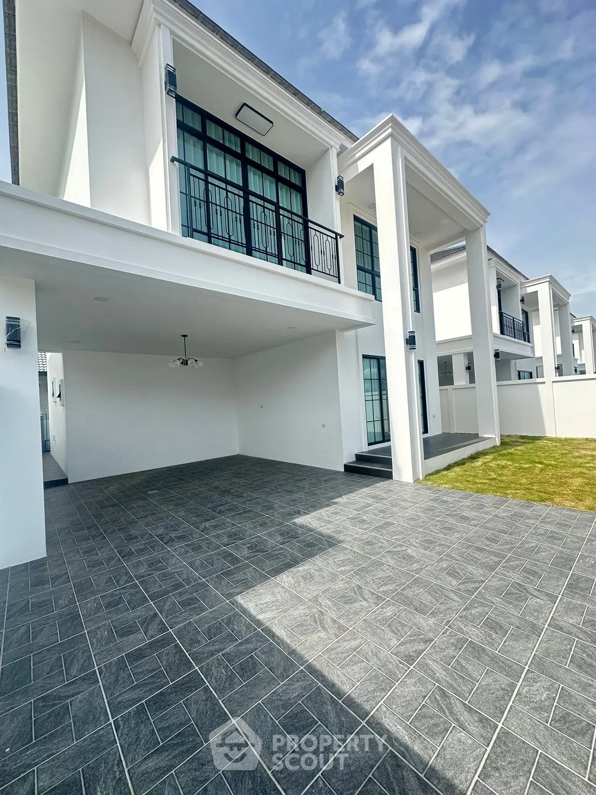 Elegant modern white building with spacious driveway and lush green lawn.