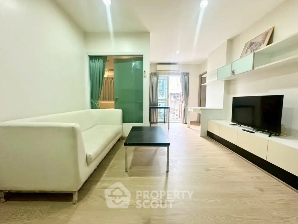 Modern living room with sleek furniture and natural light, featuring a white sofa and entertainment unit.