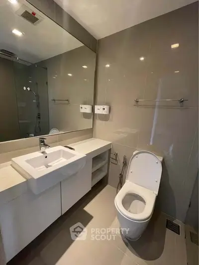 Modern bathroom with sleek fixtures and large mirror in contemporary apartment.