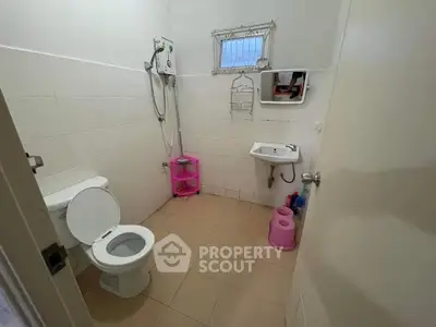 Compact bathroom with shower, toilet, and small sink in a minimalist design.