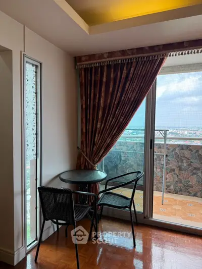 Charming balcony with glass table and chairs, offering a stunning city view through large sliding doors.