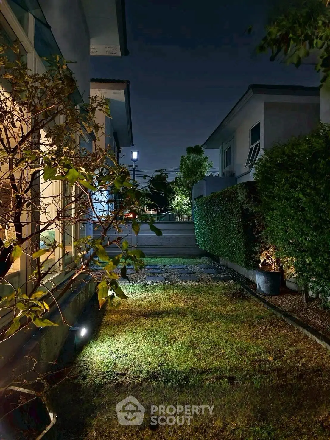 Charming night view of a residential garden with lush greenery and ambient lighting.