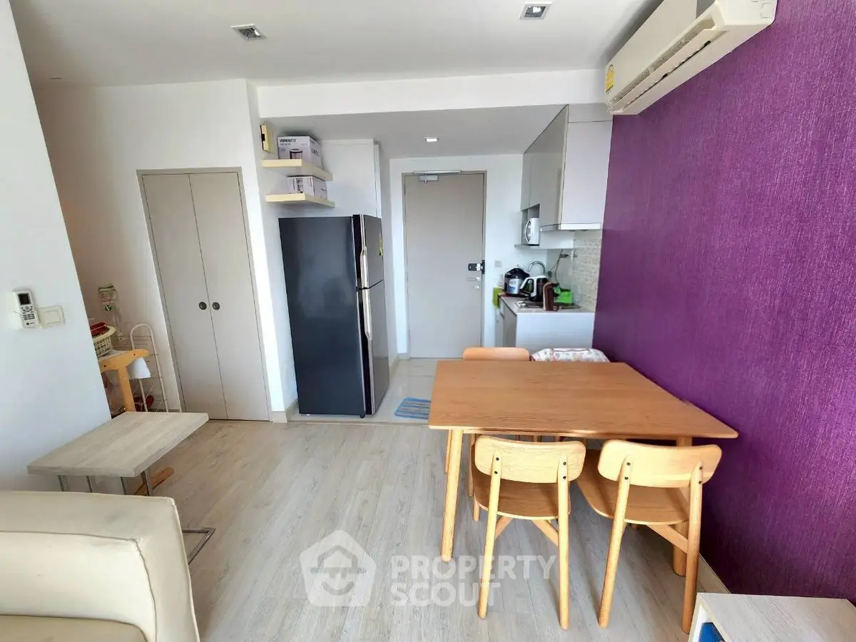 Modern dining area with vibrant purple accent wall and sleek kitchen appliances.