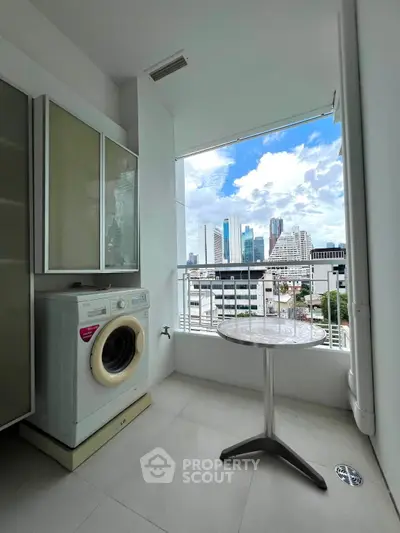 Chic urban laundry area with city skyline view, featuring a modern washing machine and compact table.