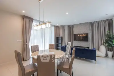 Elegant living room with modern furniture and stylish decor, featuring a round dining table and plush seating.