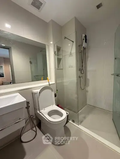 Modern bathroom with glass shower and sleek fixtures in contemporary apartment.