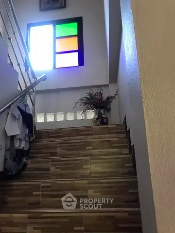 Charming staircase with colorful window and decorative vase in a cozy home setting.